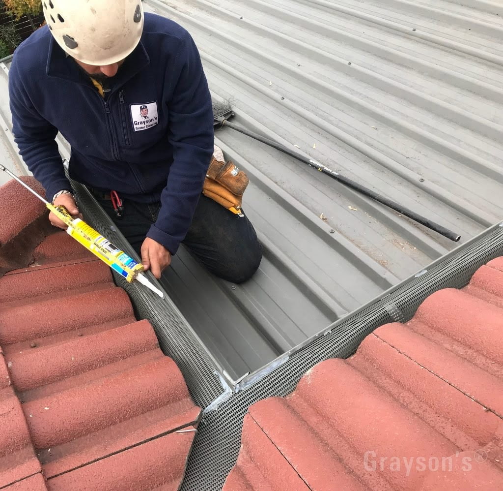 We use roof and gutter silicone to glue the Triple-G gutter protection system into place. After some time the mesh forms a permanent curled shape, the translucent silicone dries clear.