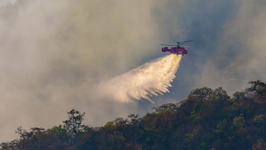 A helicopter dumping water on a bushfire